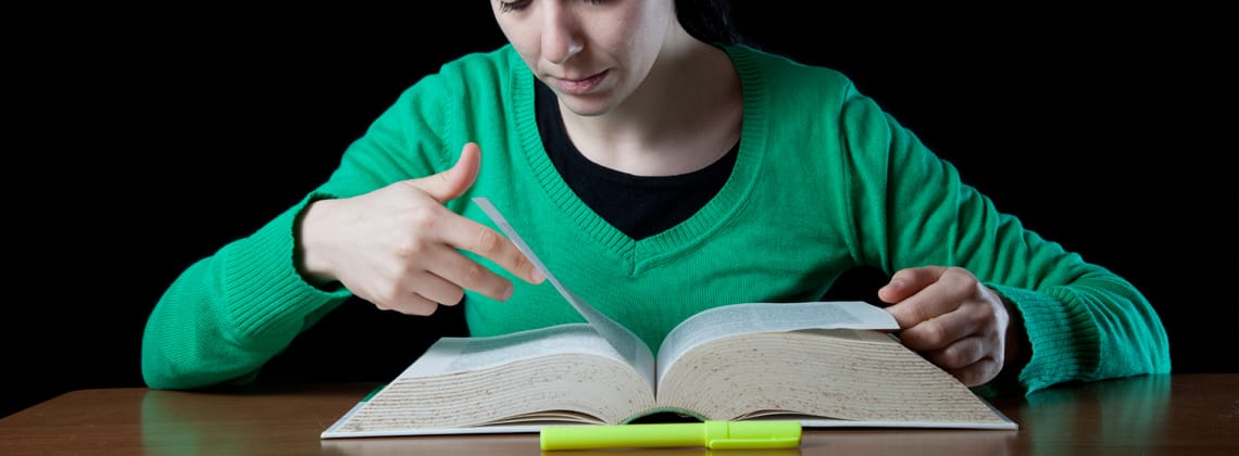 Girl searching through the dictionary's pages stock photo 25-29 Years, Adult, Adults Only, Black Background, Black Hair