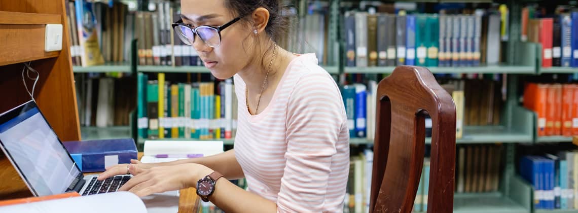 Asian student concentrating on study in library stock photo