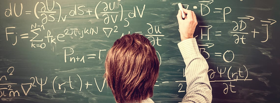 Man standing against chalkboard, solves physics equations, rear view, retro stock photo